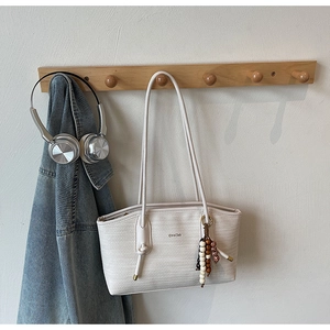 Detail of off-white woven tote bag with bead charm and Chris2ab branding on wall