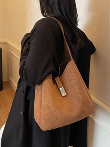 Brown suede large capacity tote bag with silver buckle worn on shoulder with black coat