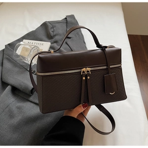 Detail of dark brown box bag with quilted texture and dual zipper closure