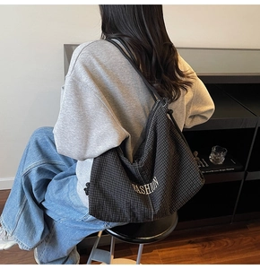 Close-up of black plaid canvas tote bag with white FASHION embroidery detail
