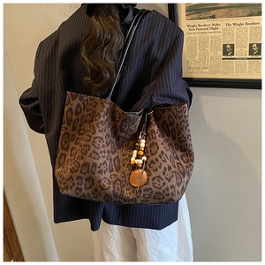 Dettaglio della borsa tote leopardata con ciondolo etnico di perline e tracolla in pelle