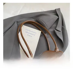 Detail of a brown matte hobo bag with wood bead charm and mixed leather textures
