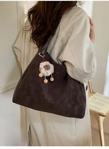 Detail of coffee brown suede tote bag with cute white sheep plush keychain accessory