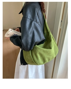 Vue détaillée d'un grand sac hobo en daim vert porté par un mannequin en intérieur