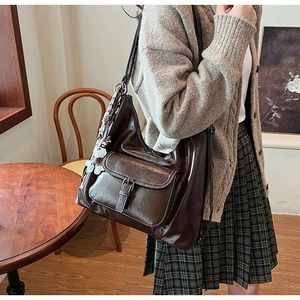 Détail du sac cabas en cuir marron avec poche à rabat, surpiqûres et charmant chiot décoratif