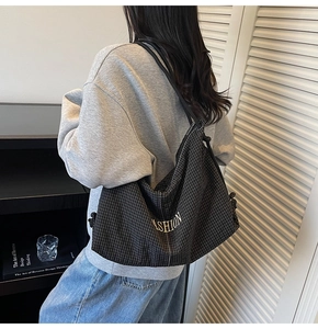 Detail of grid pattern shoulder bag with FASHION print and drawstring on a model