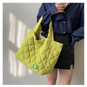 Detail of quilted bright yellow tote bag featuring a ruched handle and MISU brand label