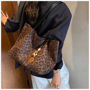 Vista dettagliata della borsa tote leopardata con ciondolo in legno perlato sulla tracolla nera