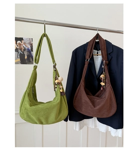 Détail de sacs demi-lune en daim vert et marron avec breloques décoratives en perles