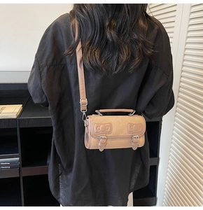 Detail of beige suede crossbody bag with bow accent and vintage buckle on the flap