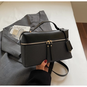 Close-up of black crossbody box bag showing dual textures and golden hardware