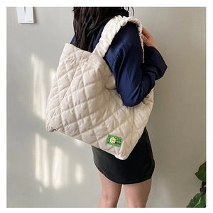 Detail of quilted corduroy shoulder bag showing the green MISU label and pleated strap