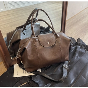 Detail of vintage brown Boston bag with textured leather and wide decorative strap