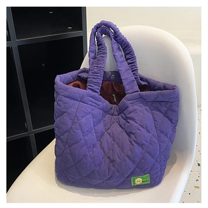 Detail view of the quilted purple tote bag featuring ruched handles and a magnetic closure