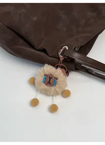 Detail of cute khaki plush sheep charm with blue facial embroidery on a brown tote bag