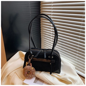 Detail of black suede patchwork shoulder bag with dual handles and plush donut charm