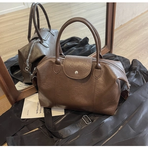 Detail view of brown vintage doctor bag with wide strap and silver metal zipper closure