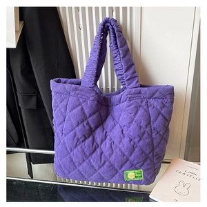 Detail of purple quilted corduroy tote bag featuring a green label and scrunchie strap