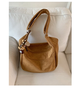 Détail d'un sac en daim avec perles en bois et pendentif cœur sur un canapé blanc