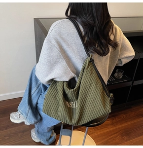 Close-up of green plaid hobo bag with yellow fashion text and black rope strap