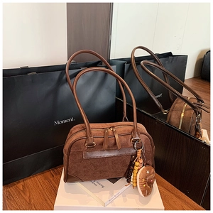 Detail view of brown matte Boston bag with leather straps and cookie bead charm