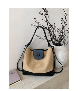 Detail of minimalist beige suede tote bag with black leather base and round button closure
