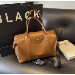 Detail of vintage brown Boston bag in textured leather with a wide lettered shoulder strap