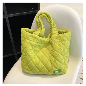 Detailed view of quilted lime green shoulder bag with ruched handle on white chair