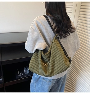 Detail of dark green checkered crossbody bag with gold Fashion print on a model