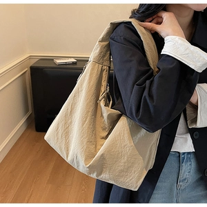 Détail d'un grand sac cabas beige avec texture en nylon plissé et accents de fermeture éclair