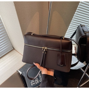 Detail of dark brown handbag showing smooth leather stitching and metal zipper