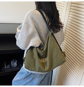 Detailed close-up of green plaid canvas shoulder bag with fashion embroidery detail