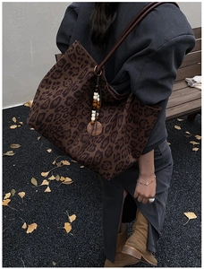 Dettaglio della borsa tote leopardata con ciondolo in legno e tracolla in pelle marrone