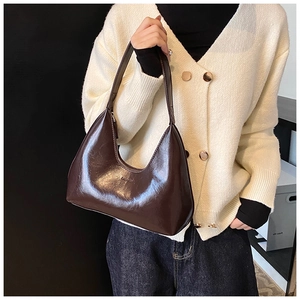 Détail du sac hobo en cuir brillant marron foncé avec inscription embossée sur la bandoulière