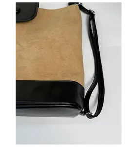 Detail view of khaki suede and black leather patchwork on a versatile tote bag