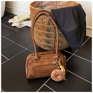 Macro detail of brown suede Boston bag featuring chocolate donut plush and wooden beads