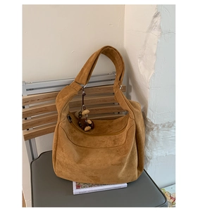Sac bandoulière en daim jaune avec pendentif en perles sur une chaise grise