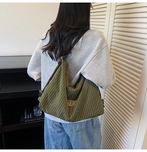 Close-up of green checkered hobo bag with yellow text and black strap detail