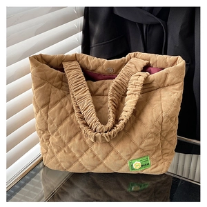 Detail of khaki quilted corduroy tote bag showing magnetic closure and logo patch