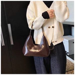 Détail d'un sac dumpling marron foncé brillant au style rétro et à la finition lisse