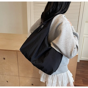 Photo lifestyle d'un grand sac hobo noir avec texture plissée et détail de fermeture éclair