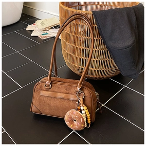 Detail of vintage brown suede pillow bag with plush donut pendant and beaded charm