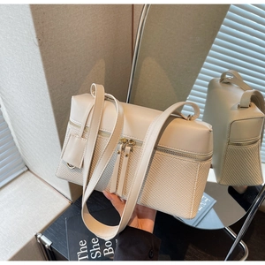 Detail of minimalist cream handbag featuring leather and woven texture contrast with metal zips