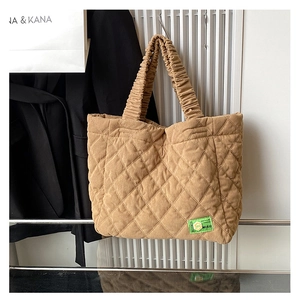 Detail of khaki quilted corduroy tote bag with ruffled handle and green brand label