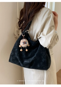 Close-up of black matte suede tote bag featuring a cute khaki plush monster charm