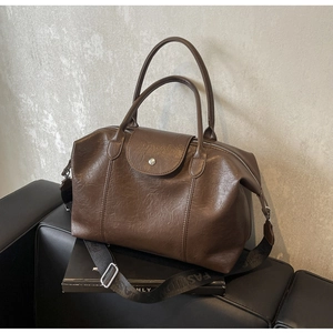 Detail of vintage brown tote bag featuring textured leather and a branded wide strap