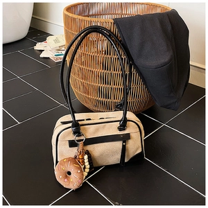 Detail of beige canvas tote with black leather trim and cute donut plush charm decoration