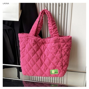 Detail of pink quilted corduroy tote bag featuring a green MISU brand label and ruched handles