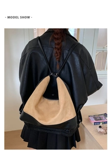 Model wearing a dual-tone khaki and black matte leather backpack showing drape and fit