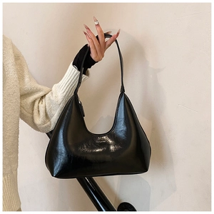 Détail du sac hobo noir brillant montrant sa texture éclatante et sa forme incurvée élégante